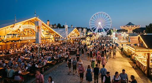 Abendstimmung auf einem großen Volksfest mit Festzelten, Riesenrad und vielen Menschen in Tracht